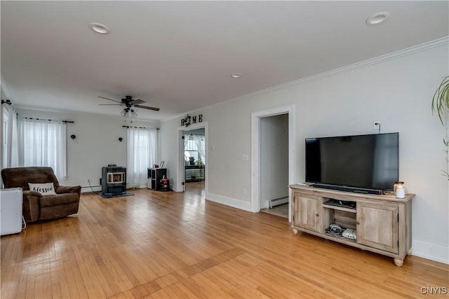 living room featuring light wood-type flooring, ornamental molding, ceiling fan, a baseboard heating unit, and a wood stove