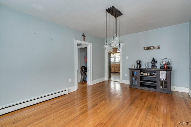 unfurnished dining area with baseboard heating and hardwood / wood-style floors