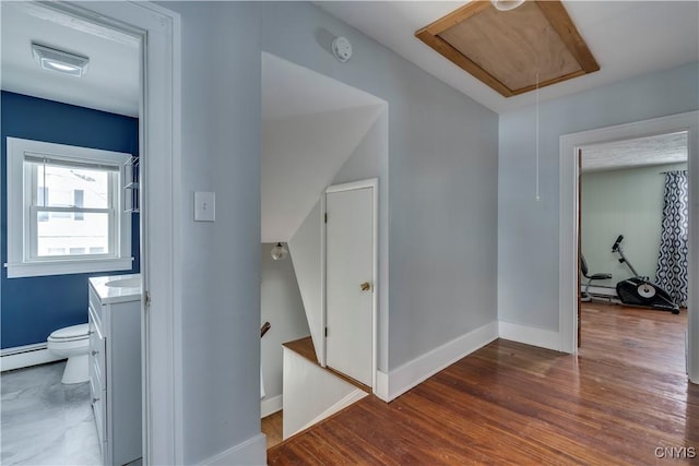 hallway with dark wood-type flooring and a baseboard radiator