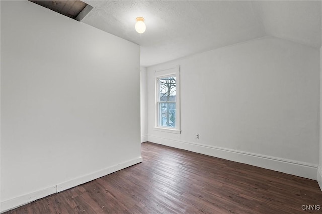 spare room with dark hardwood / wood-style flooring, lofted ceiling, and a textured ceiling