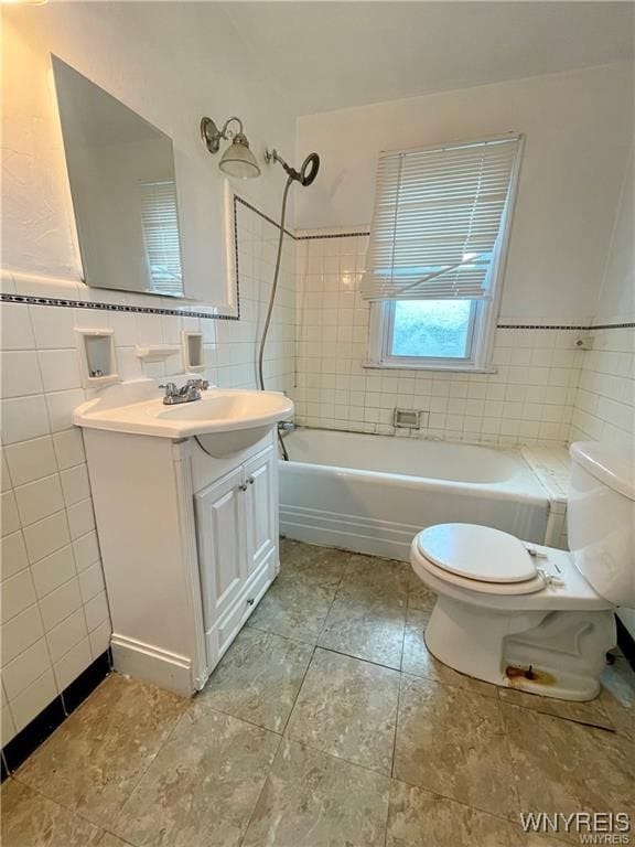 full bathroom featuring vanity, tiled shower / bath combo, toilet, and tile walls