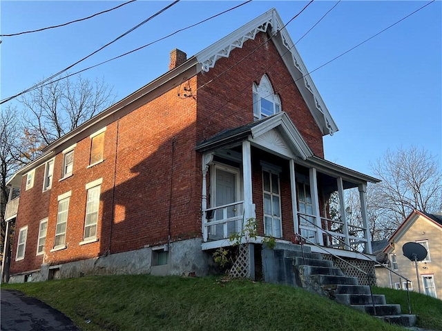 view of property exterior with covered porch and a lawn