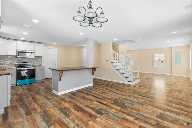 kitchen featuring appliances with stainless steel finishes, a kitchen breakfast bar, tasteful backsplash, dark wood-type flooring, and white cabinets