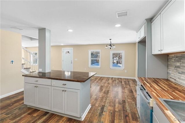 kitchen with a chandelier, dark hardwood / wood-style floors, stainless steel dishwasher, and butcher block counters