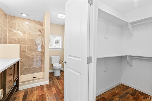 bathroom with a shower, vanity, hardwood / wood-style flooring, and toilet