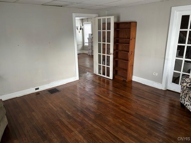 spare room with a paneled ceiling, dark hardwood / wood-style floors, and french doors