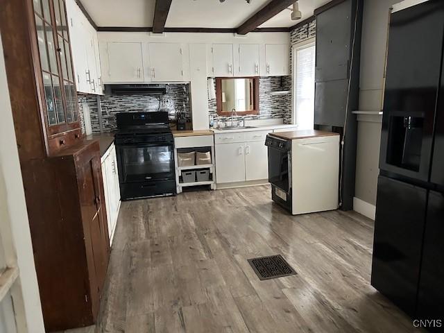 kitchen featuring beam ceiling, wood-type flooring, black appliances, and white cabinets