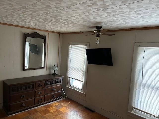 interior space with ceiling fan, ornamental molding, and light parquet floors