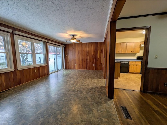 unfurnished living room featuring a textured ceiling, dark hardwood / wood-style flooring, ceiling fan, and wood walls