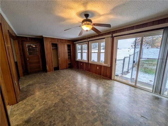 spare room with ceiling fan, wooden walls, and a textured ceiling