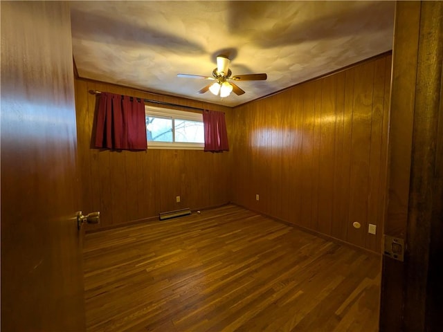 unfurnished room with wood walls, ceiling fan, and wood-type flooring