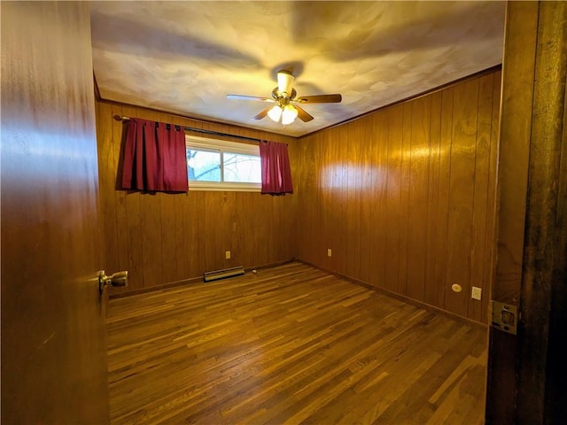 unfurnished room with wooden walls, hardwood / wood-style floors, and ceiling fan