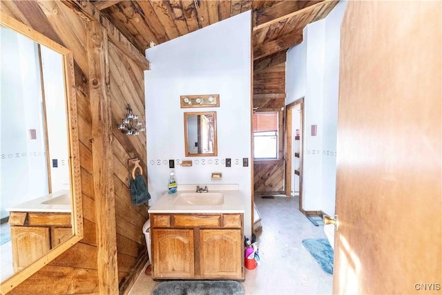 bathroom with concrete flooring, wood walls, wood ceiling, vaulted ceiling, and vanity