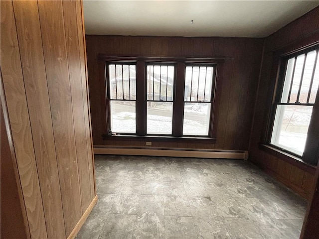 spare room featuring a wealth of natural light, wooden walls, and a baseboard heating unit