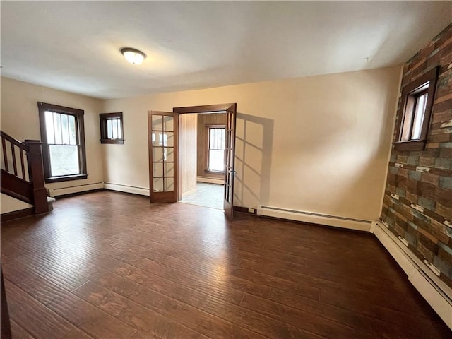 spare room featuring french doors, dark hardwood / wood-style flooring, and a baseboard heating unit