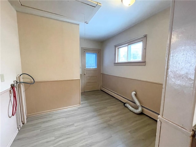 laundry area with light wood-type flooring and a baseboard radiator