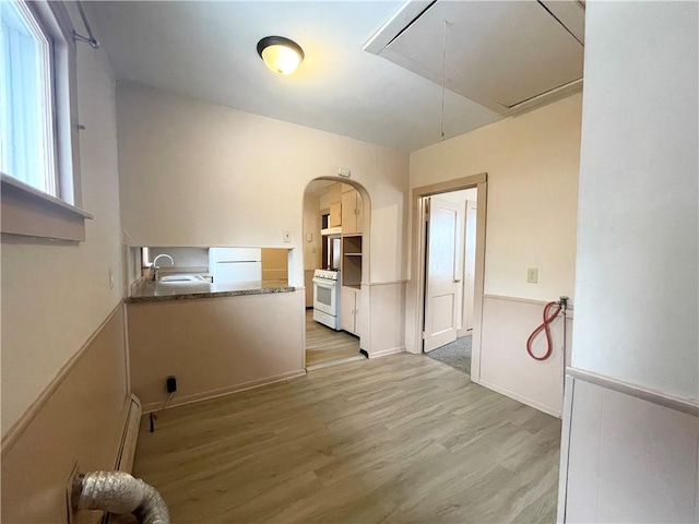 interior space with baseboard heating, sink, and light hardwood / wood-style floors