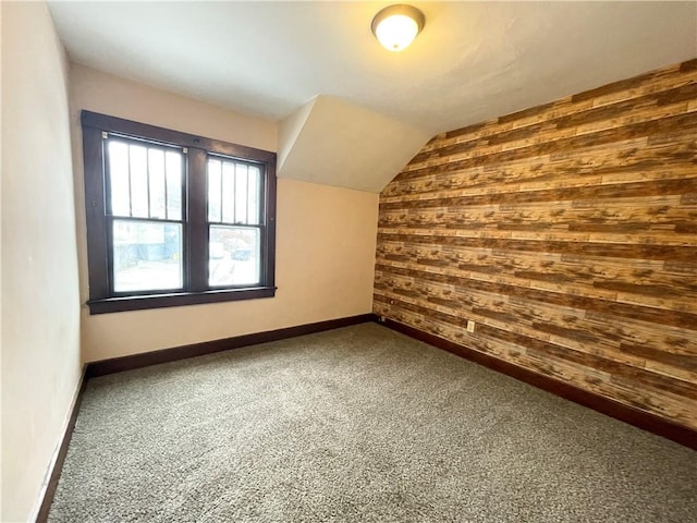 bonus room featuring wood walls, carpet floors, and vaulted ceiling