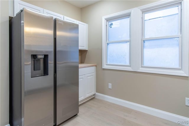 kitchen with white cabinets, stainless steel fridge, and light hardwood / wood-style floors