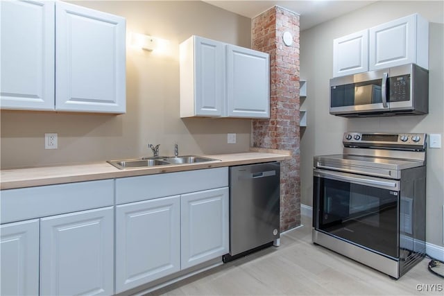 kitchen featuring appliances with stainless steel finishes, light hardwood / wood-style floors, white cabinetry, and sink