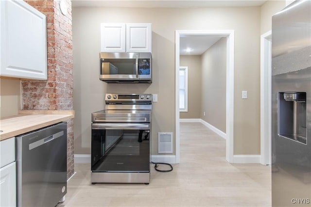 kitchen featuring white cabinets, stainless steel appliances, and light hardwood / wood-style flooring