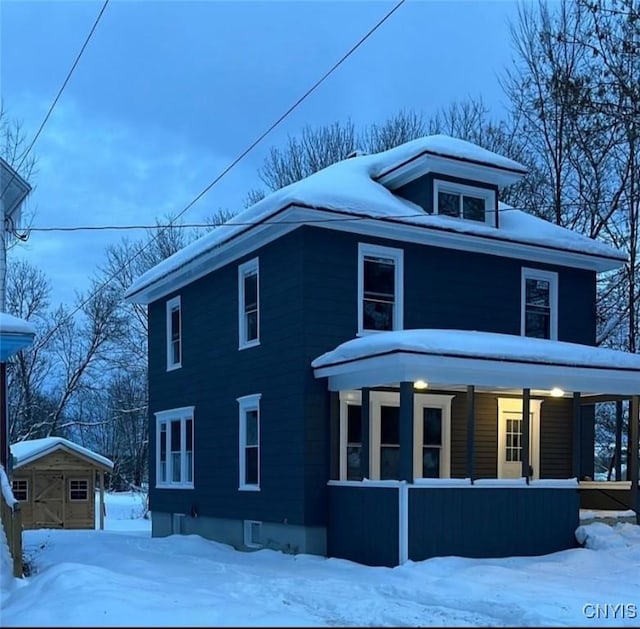 view of front facade featuring covered porch and a storage shed