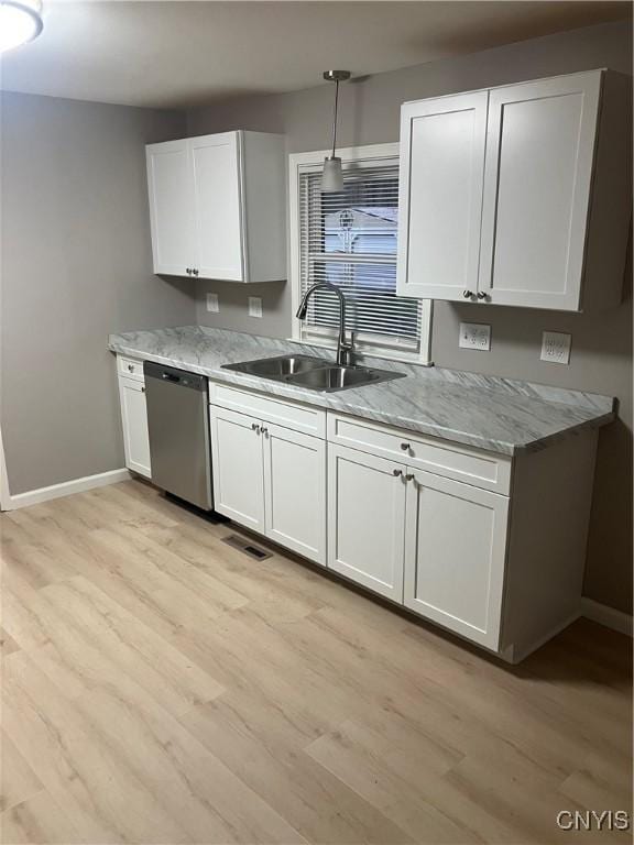 kitchen featuring dishwasher, white cabinets, sink, light wood-type flooring, and light stone counters