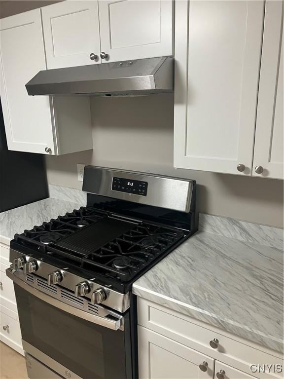 kitchen featuring gas stove, light stone countertops, and white cabinets