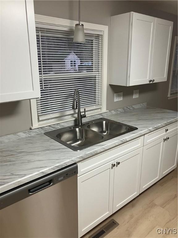 kitchen featuring dishwasher, white cabinets, sink, light hardwood / wood-style flooring, and decorative light fixtures