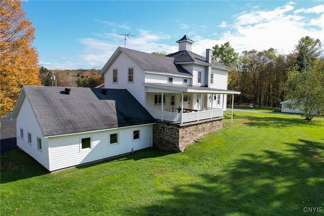 rear view of house featuring a lawn and covered porch