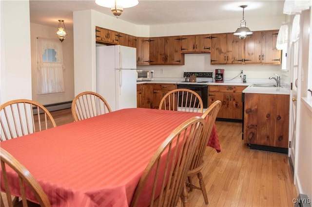 kitchen with sink, baseboard heating, light hardwood / wood-style floors, decorative light fixtures, and white appliances