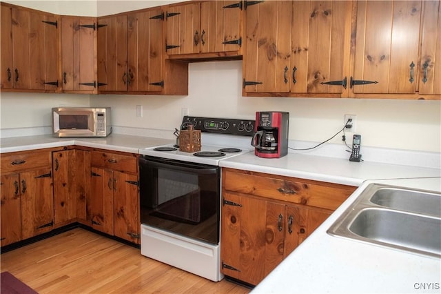 kitchen with white range with electric stovetop, sink, and light wood-type flooring