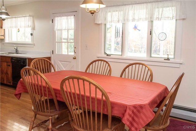 dining room featuring hardwood / wood-style floors, a healthy amount of sunlight, sink, and a baseboard radiator