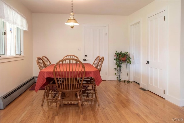 dining space with a baseboard radiator and light hardwood / wood-style flooring