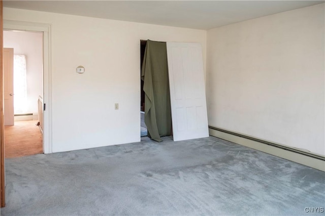 carpeted spare room with a baseboard heating unit