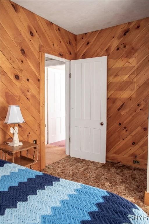 unfurnished bedroom featuring carpet and wood walls