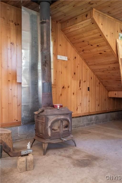 interior space with a wood stove, wooden walls, and wooden ceiling