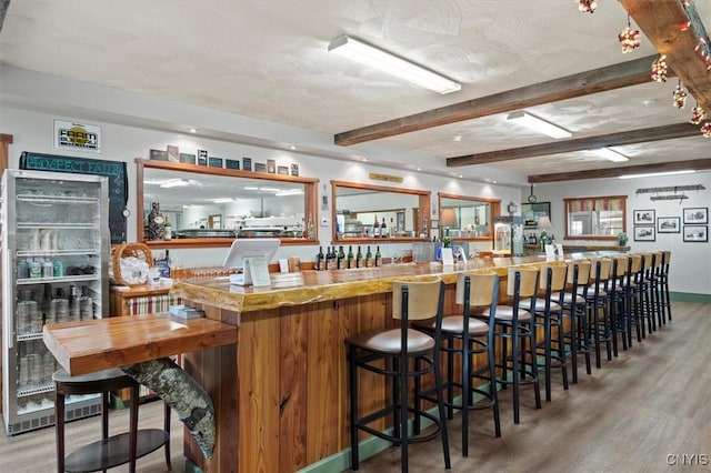 bar featuring hardwood / wood-style flooring, beamed ceiling, and beverage cooler