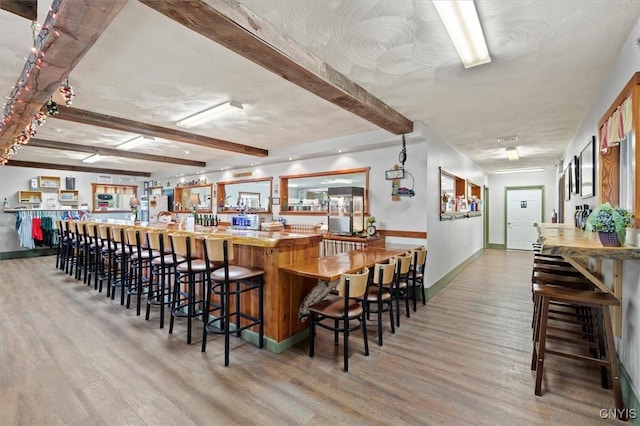 bar with beam ceiling and light hardwood / wood-style floors