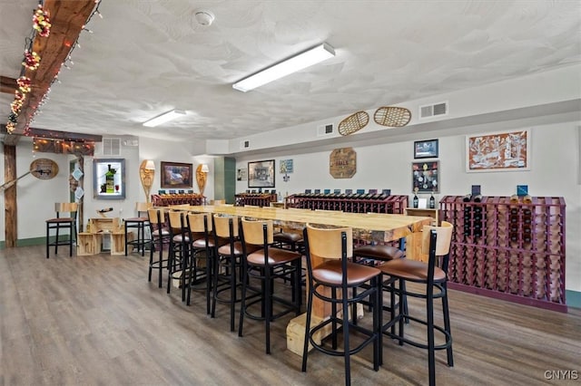 bar with a textured ceiling and hardwood / wood-style flooring