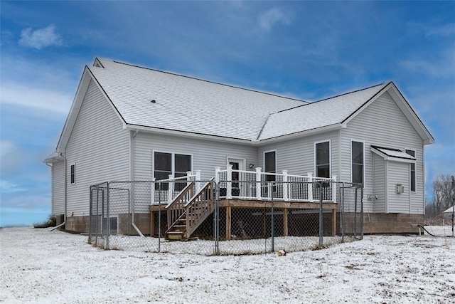 snow covered back of property with a deck