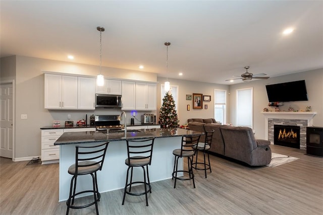 kitchen featuring white cabinets, pendant lighting, an island with sink, and appliances with stainless steel finishes