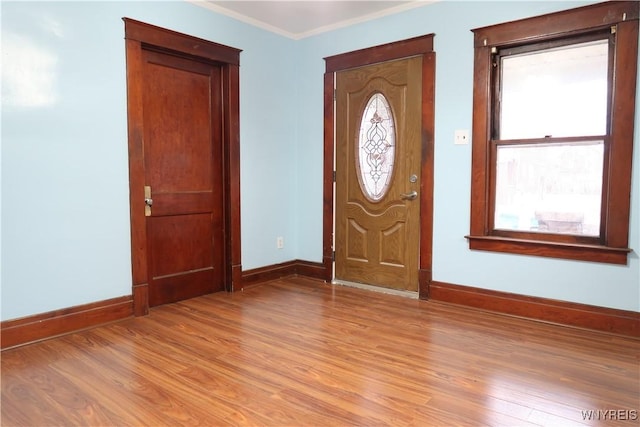 entryway with plenty of natural light, ornamental molding, and light hardwood / wood-style flooring