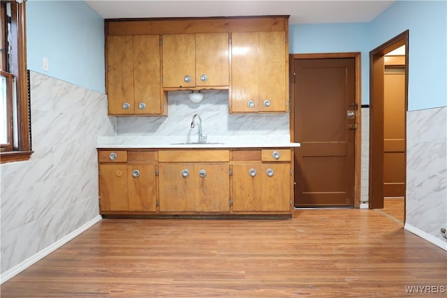 kitchen with sink, tile walls, and light hardwood / wood-style flooring