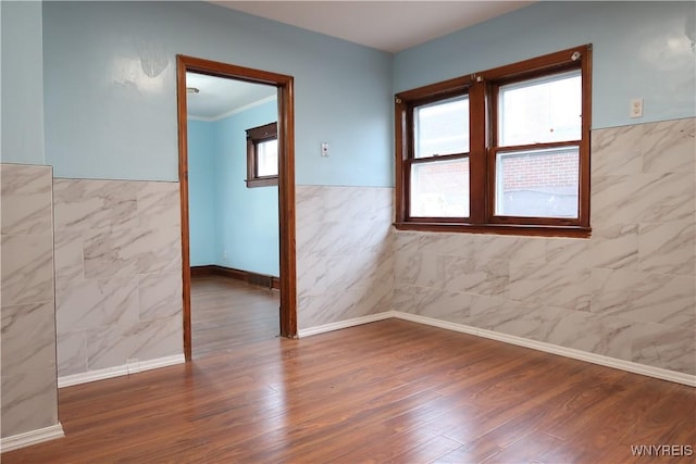 spare room with hardwood / wood-style floors, tile walls, and ornamental molding