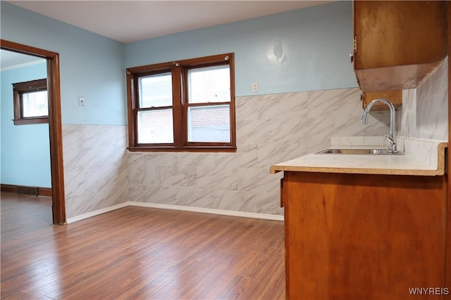 kitchen with hardwood / wood-style floors, tile walls, and sink