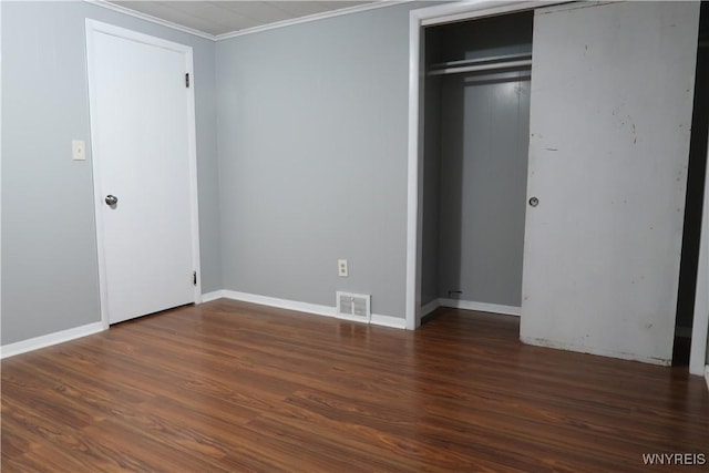 unfurnished bedroom featuring dark hardwood / wood-style floors, ornamental molding, and a closet