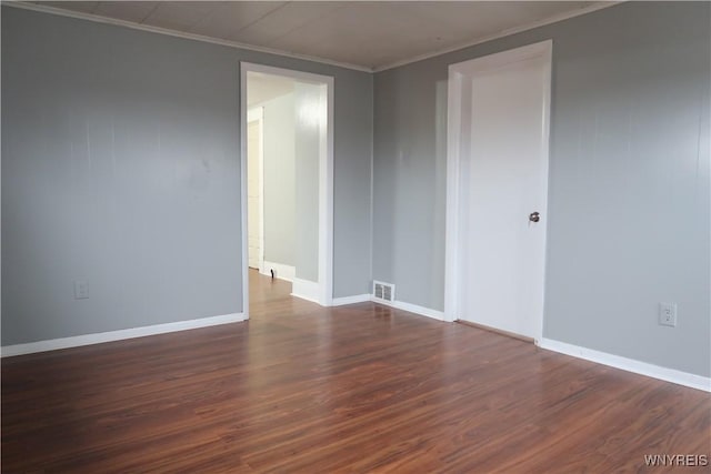 spare room with crown molding and dark wood-type flooring