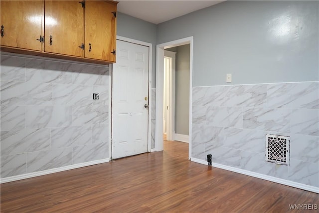 interior space with hardwood / wood-style floors and tile walls