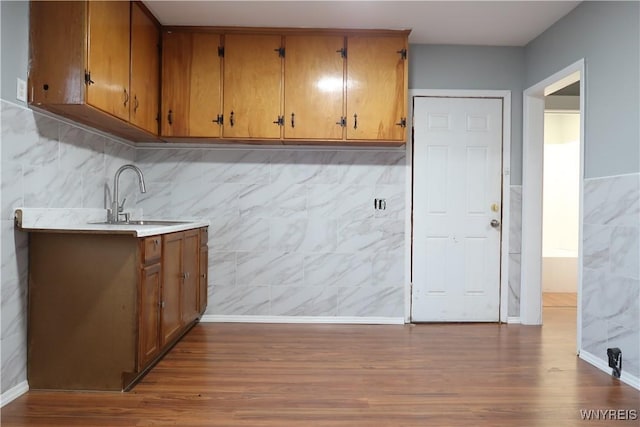 kitchen featuring light wood-type flooring, sink, and tile walls